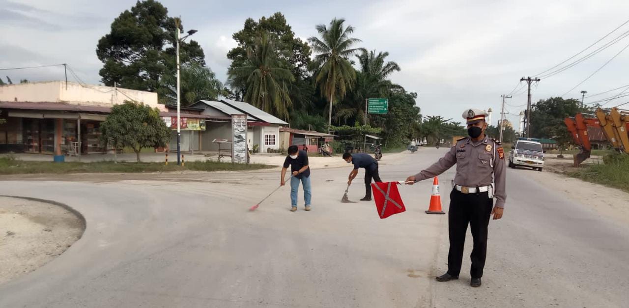 Satlantas Polsek Tualang Bersihkan Pasir dan Tanah Menumpuk di Badan Jalan.
